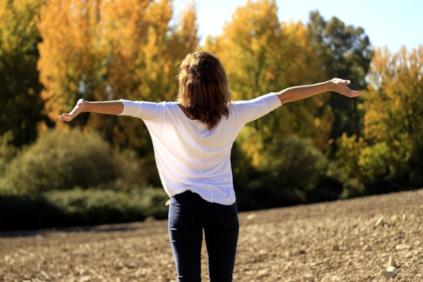 Femme en extérieur qui pratique face à la nature les exercices qu’elle a découvert avec les packs vidéos de sophrologie à faire n’importe où, n’importe quand.