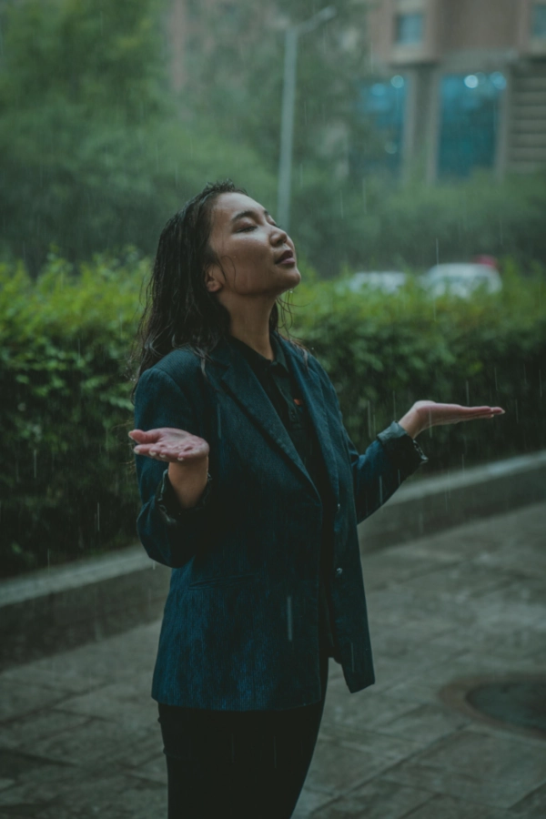 Définition de la sophrologie à travers cette femme qui reste sous la pluie et accueille les sensations que lui procurent le contact des gouttes avec le corps.