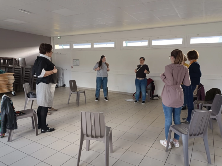 Animation d'une séance de sophrologie en association, près de Rouen, pendant laquelle les particicpantes sont debout placées en cercle en train de faire des exercices de relaxation dynamique.